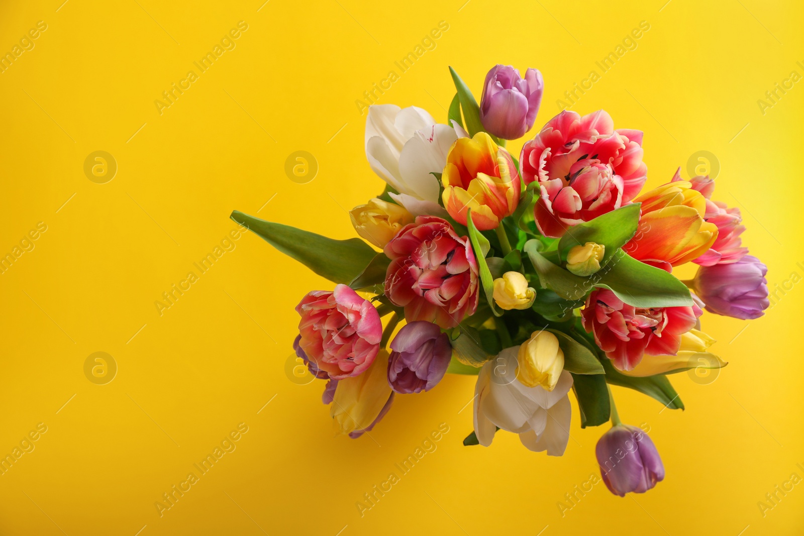 Photo of Bouquet of beautiful tulips on yellow background, top view. Space for text