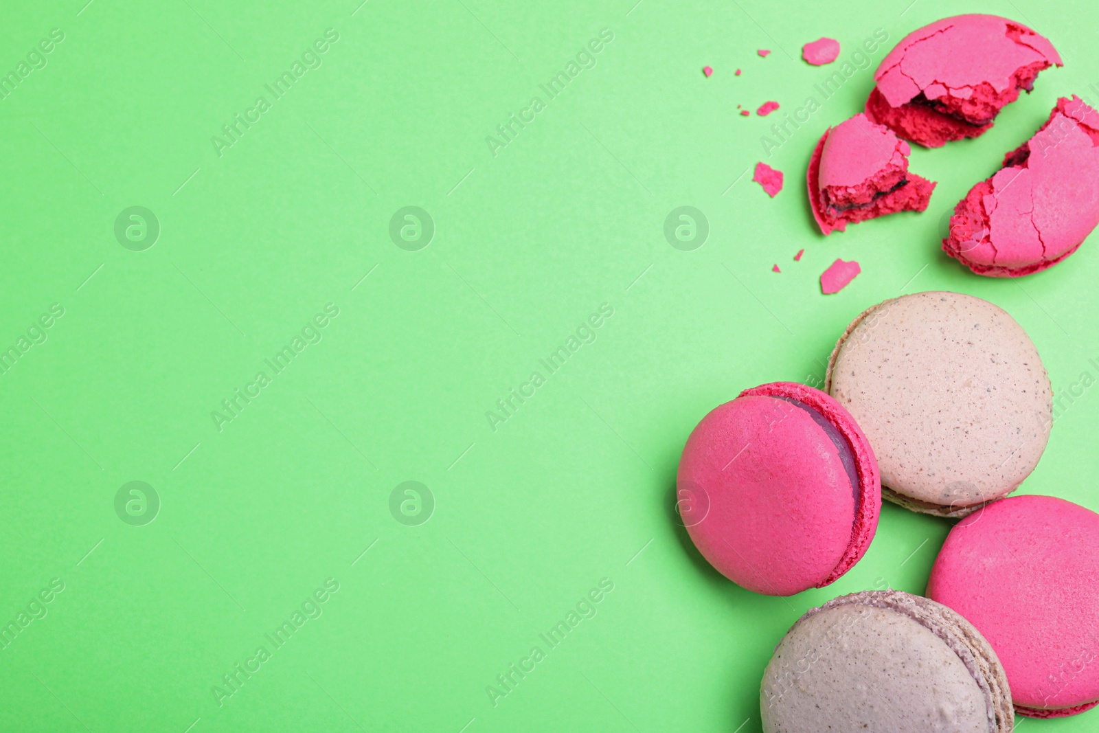 Photo of Delicious colorful macarons on green background, flat lay. Space for text