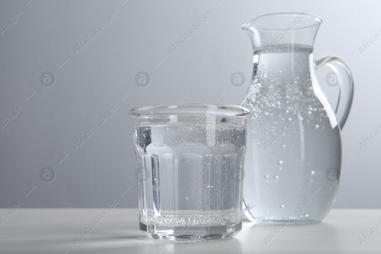 Photo of Glassware with soda water on white wooden table. Space for text