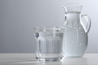 Photo of Glassware with soda water on white wooden table. Space for text