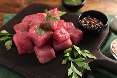 Cooking delicious goulash. Raw beef meat with parsley and spices on table, closeup