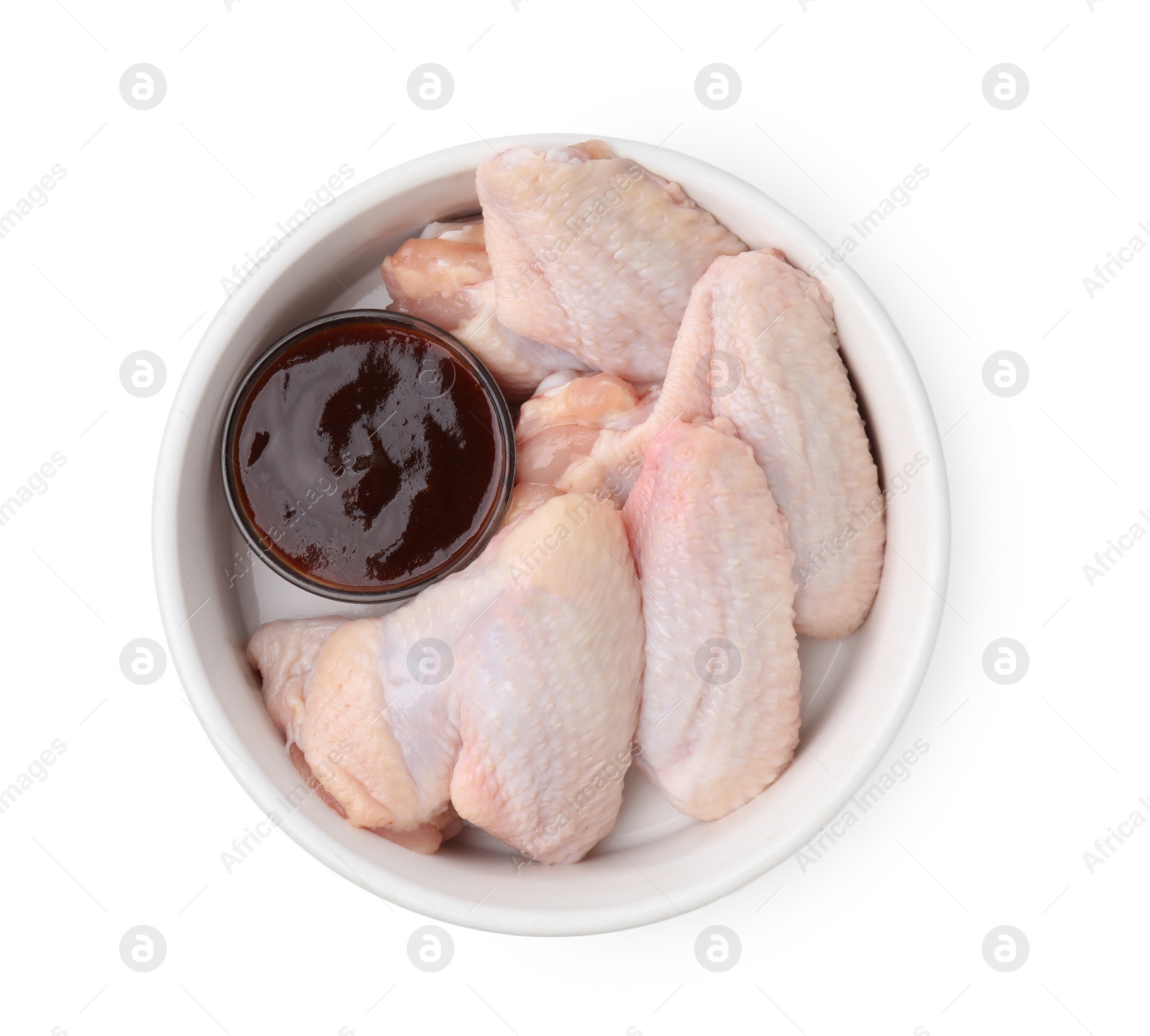 Photo of Fresh marinade and raw chicken wings in bowl isolated on white, top view