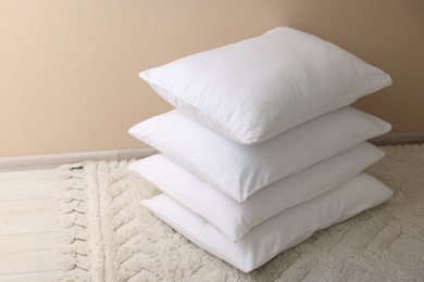 Photo of Stack of soft white pillows near beige wall indoors. Space for text