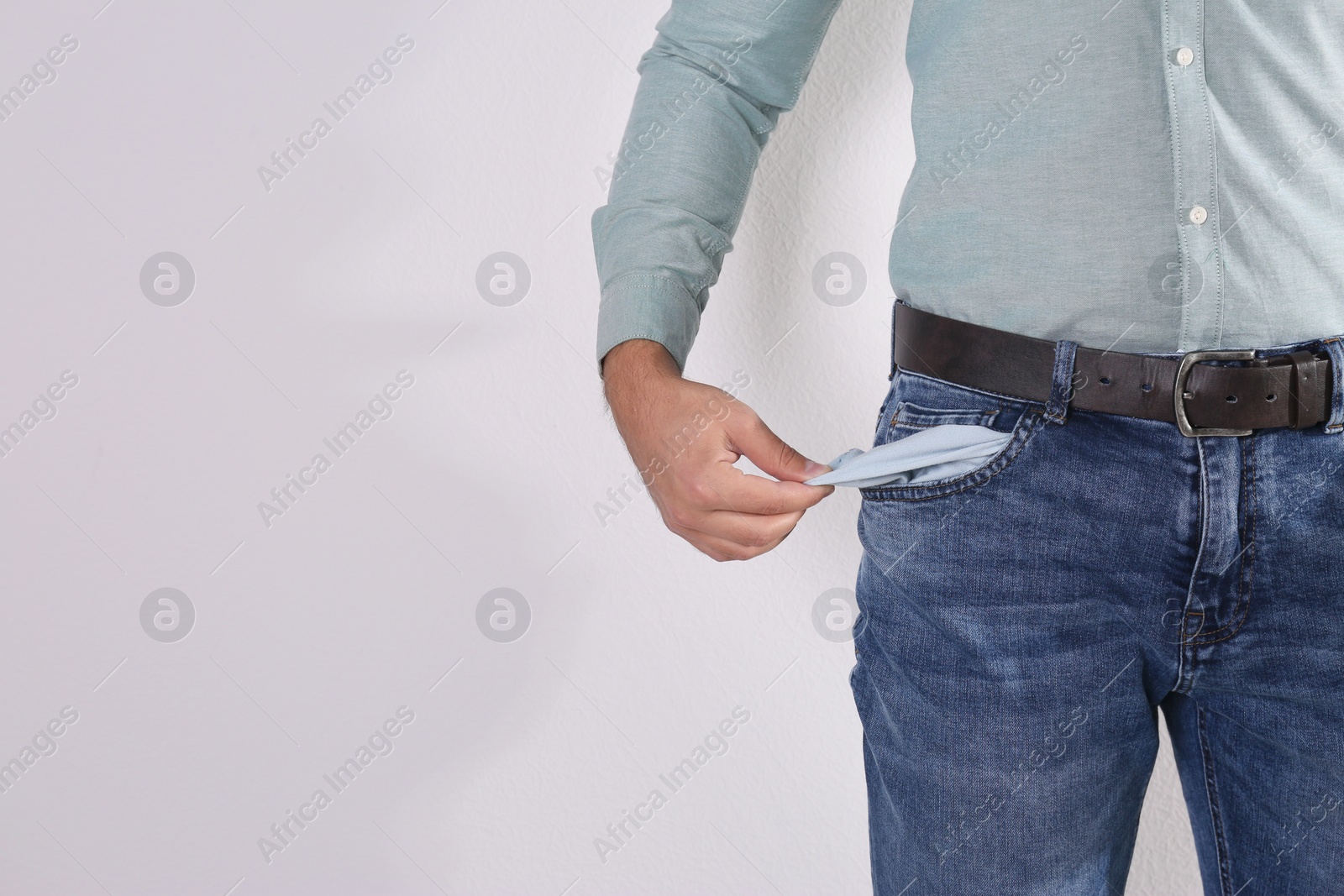 Photo of Man showing empty pocket on light background, closeup. Space for text