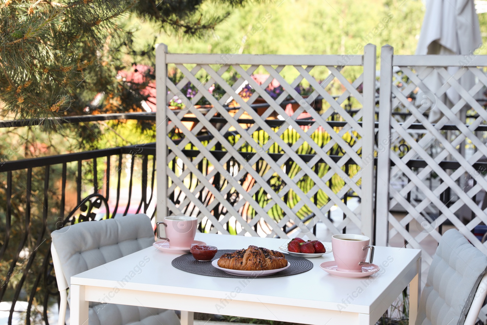 Photo of Outdoor breakfast with tea and croissants on white table on terrace