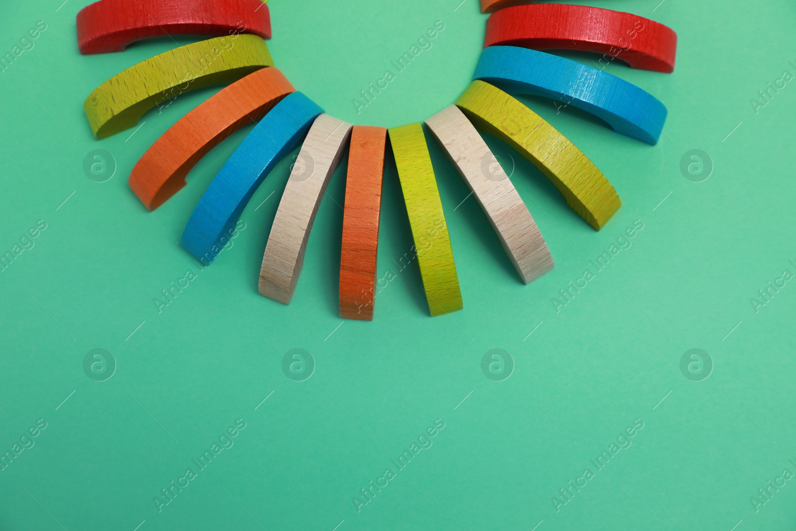 Photo of Colorful wooden pieces of play set on green background, flat lay with space for text. Educational toy for motor skills development