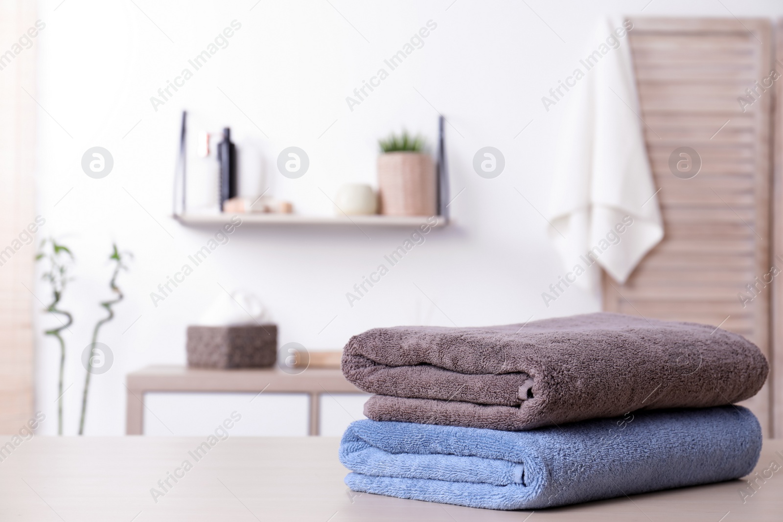 Photo of Stack of fresh towels on table in bathroom. Space for text