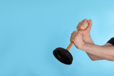 Photo of Man holding plunger on turquoise background, closeup. Space for text