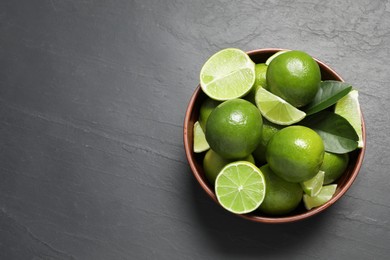 Fresh ripe limes in bowl on black table, top view. Space for text