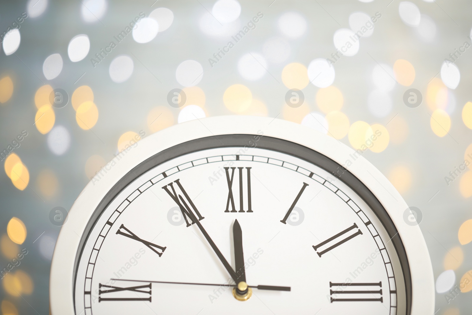 Photo of Clock showing five minutes until midnight on blurred background, closeup. New Year countdown