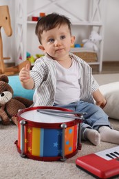 Photo of Cute little boy with toy drum at home