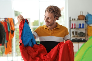 Young man choosing sleeping bag in store