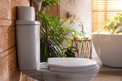 Photo of Stylish bathroom interior with toilet bowl and green plants