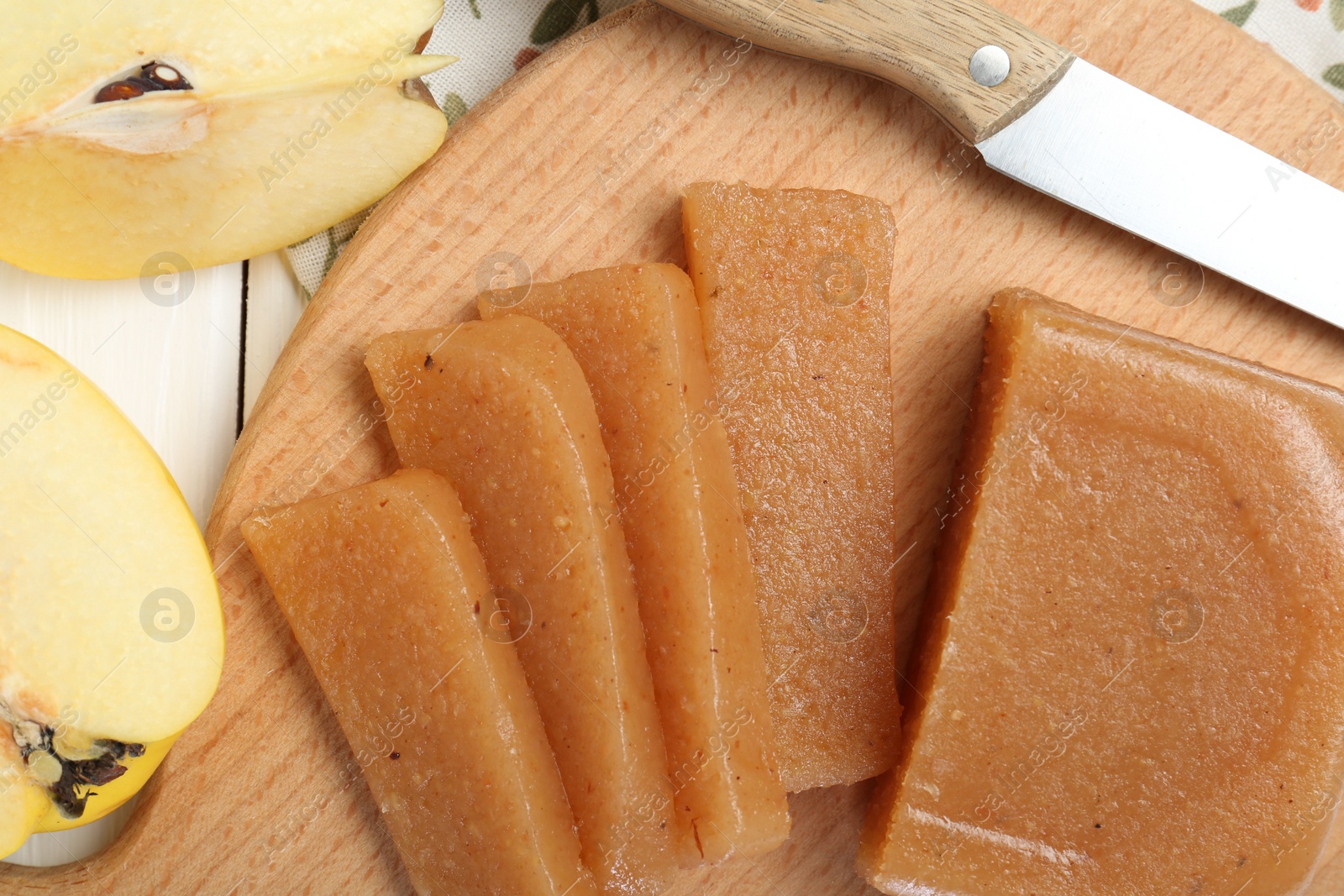 Photo of Tasty sweet quince paste, fresh fruits and knife on white wooden table, flat lay