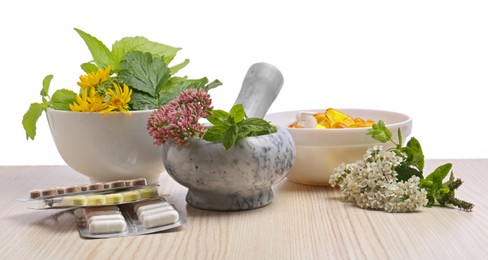 Mortar with fresh herbs and pills on white background