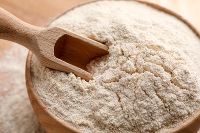 Photo of Quinoa flour in wooden bowl and scoop, closeup