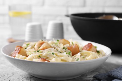 Photo of Delicious scallop pasta with spices in bowl on gray table, closeup