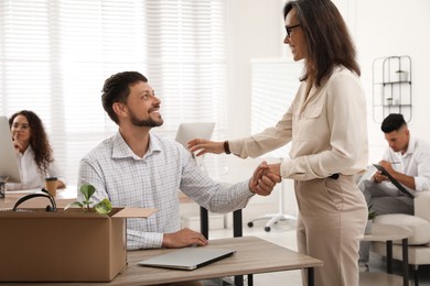 Boss shaking hand with new coworker in office