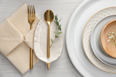 Photo of Elegant cutlery with green leaves on table, flat lay. Festive setting