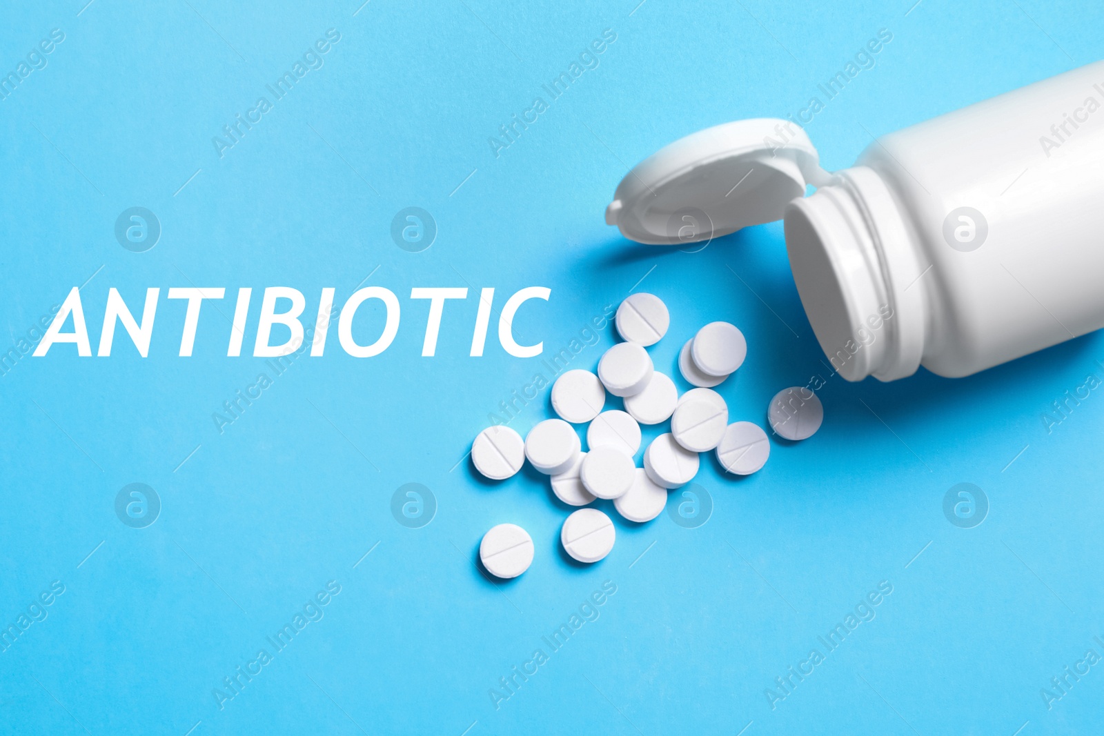 Image of Word Antibiotic, pills and bottle on light blue background, above view