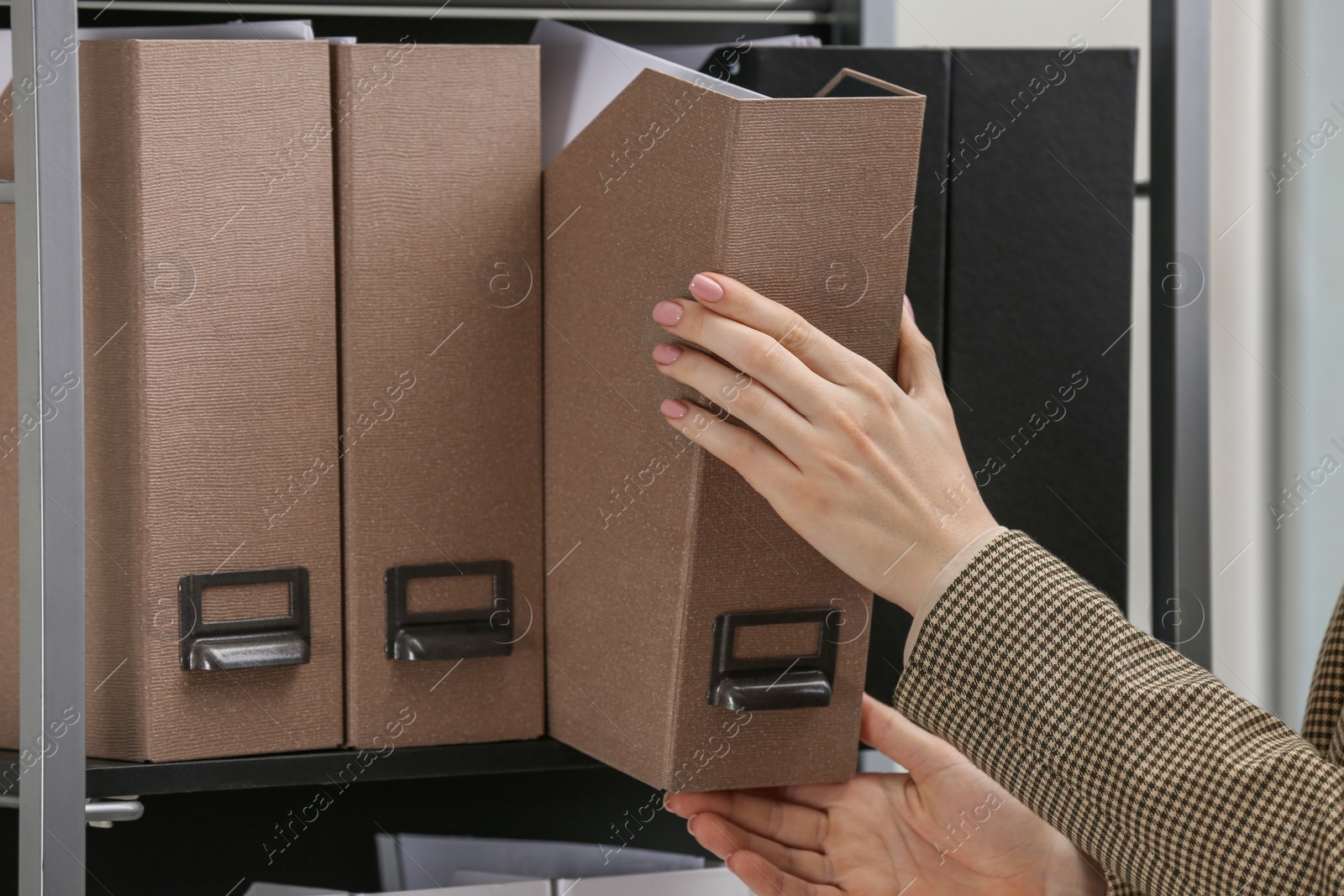 Photo of Woman taking folder with documents from shelf in office, closeup