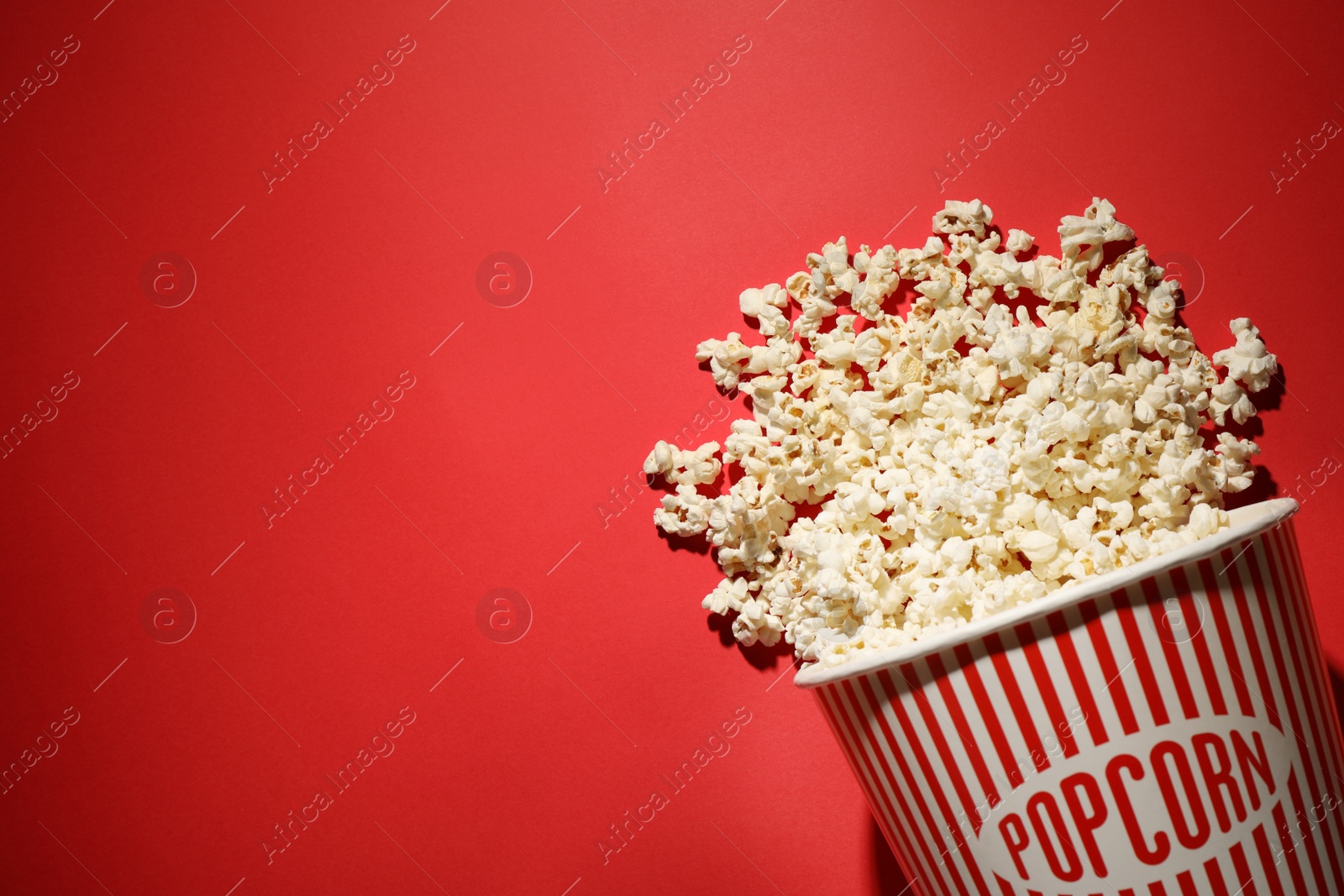 Photo of Delicious popcorn on red background, top view. Space for text