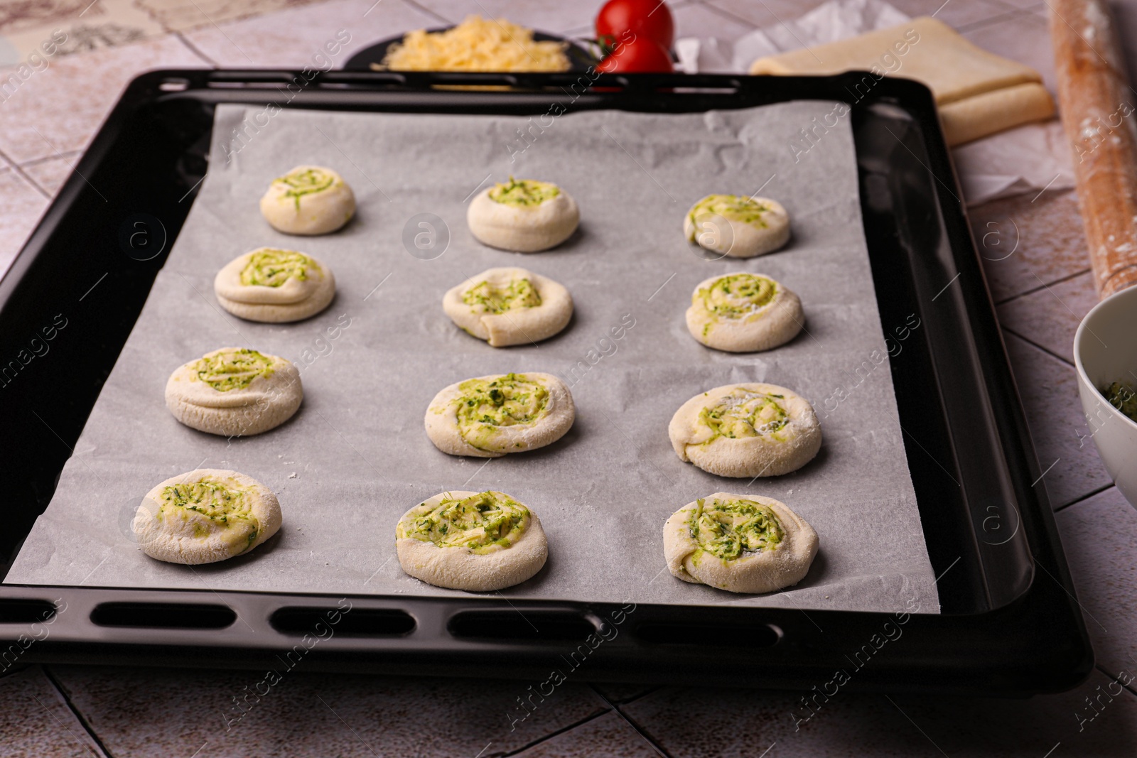 Photo of Baking sheet with raw puff pastry on tiled table