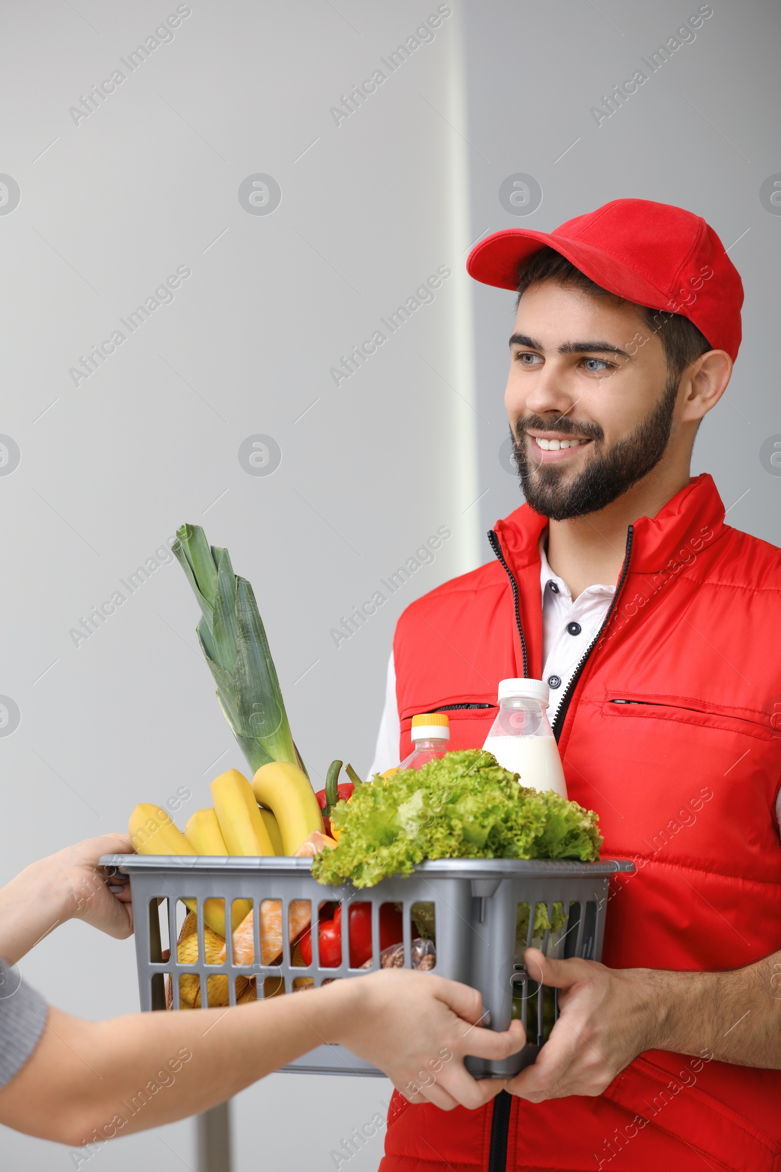 Photo of Young man delivering food to customer indoors