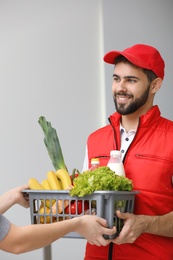 Photo of Young man delivering food to customer indoors