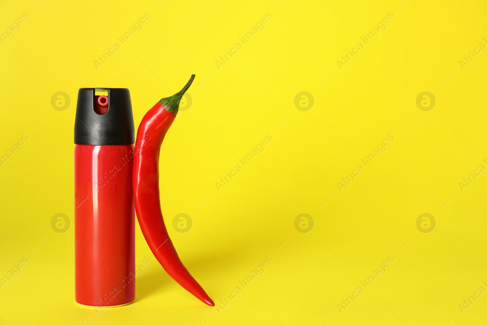 Photo of Bottle of gas spray and fresh chili pepper on yellow background. Space for text