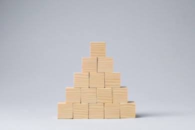 Photo of Pyramid of blank wooden cubes on light grey background