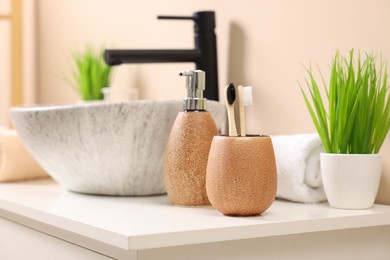 Different bath accessories and personal care products near sink on bathroom vanity