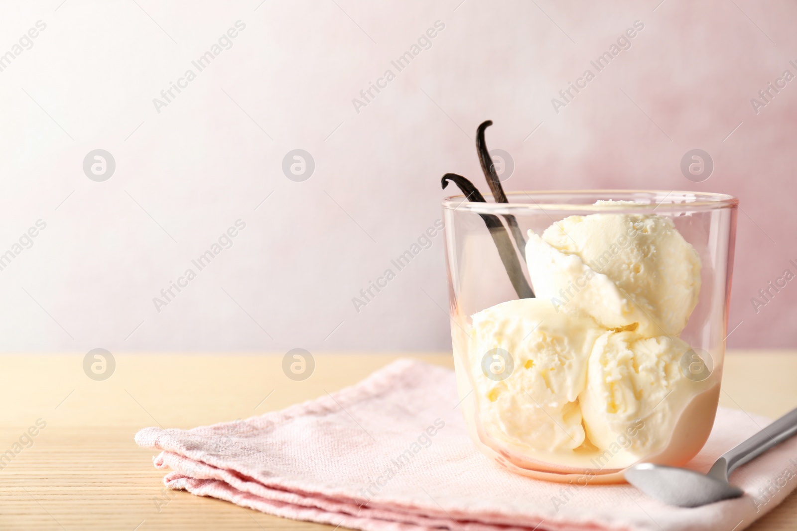 Photo of Glass with tasty vanilla ice cream on wooden table