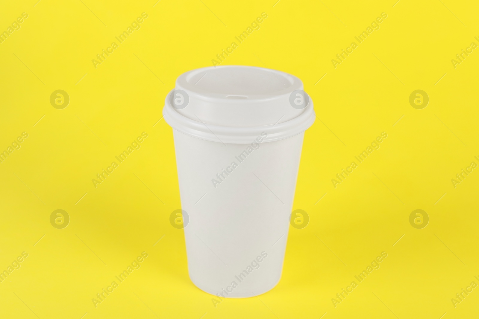 Photo of Paper cup with plastic lid on yellow background. Coffee to go