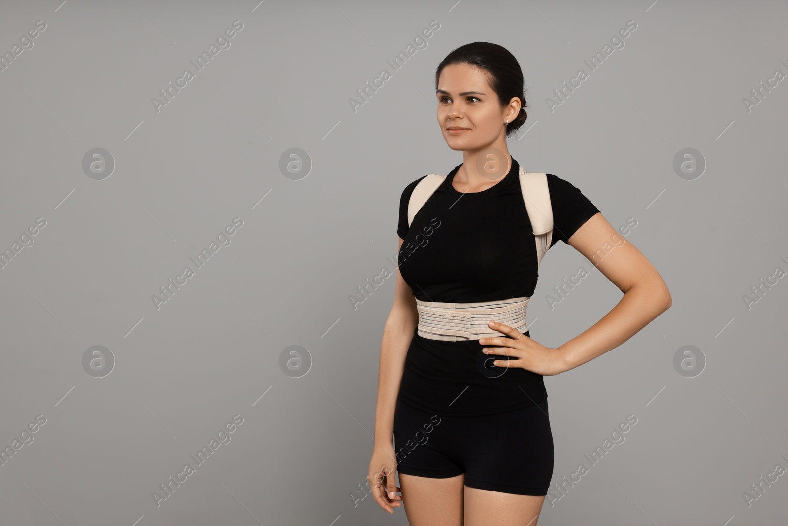 Photo of Beautiful woman with orthopedic corset on grey background, space for text