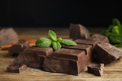 Tasty chocolate pieces and mint on wooden table, closeup