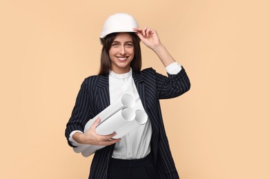 Photo of Architect in hard hat with drafts on beige background