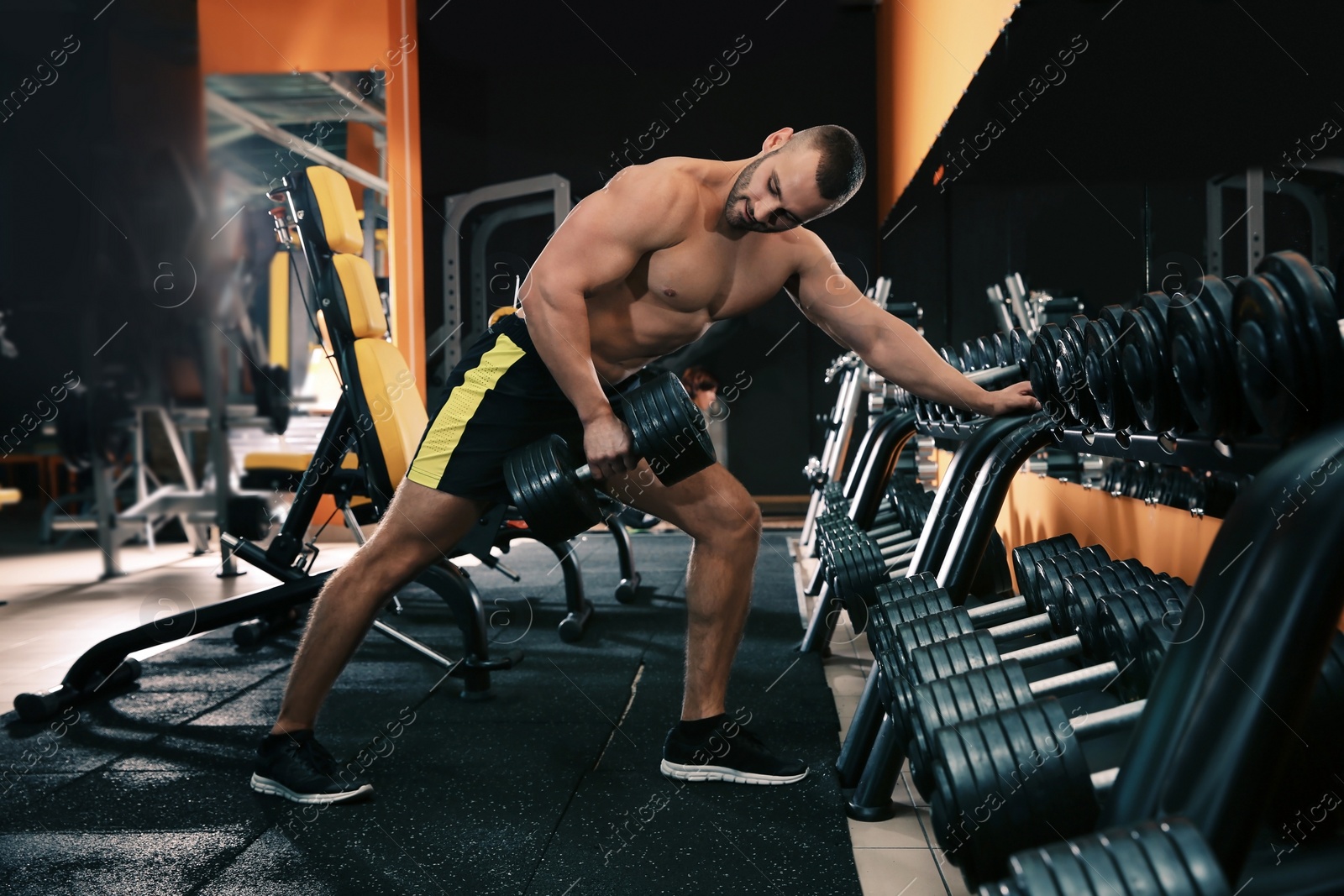 Photo of Strong young man lifting dumbbell in gym