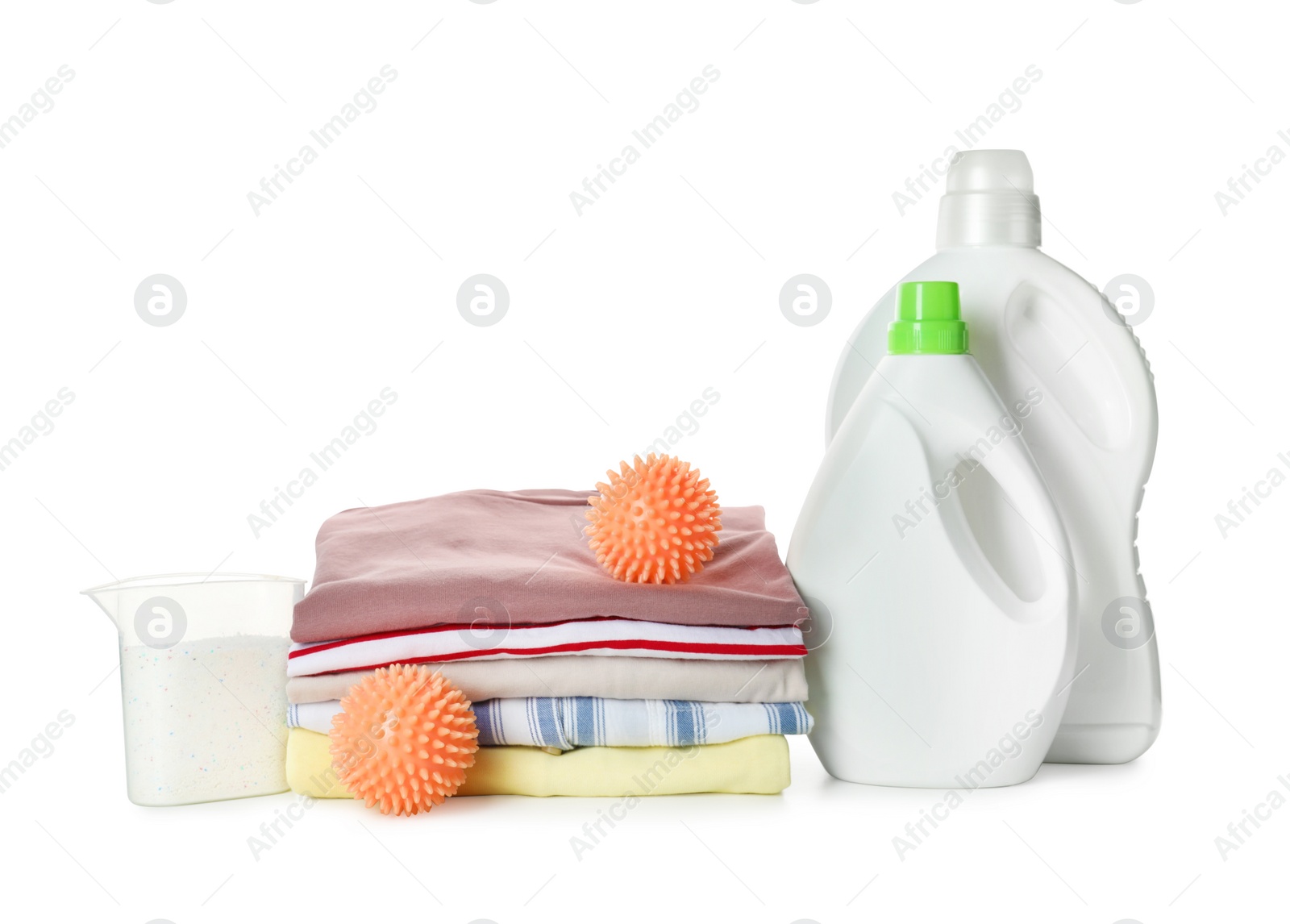 Photo of Orange dryer balls, detergents and stacked clean clothes on white background