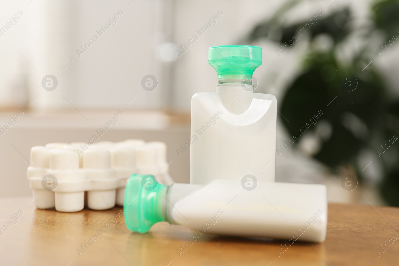 Photo of Mini bottles of cosmetic products and soap on wooden table against blurred background, closeup