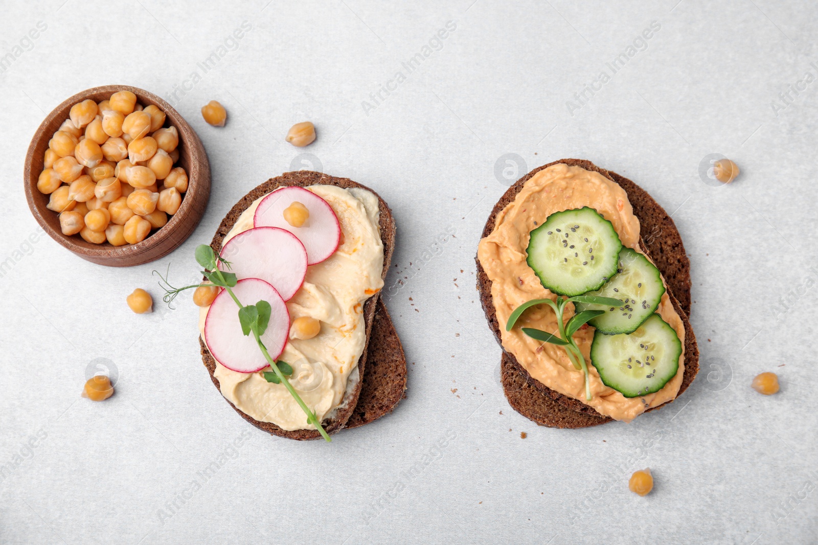 Photo of Delicious sandwiches with hummus and different ingredients on white background, flat lay