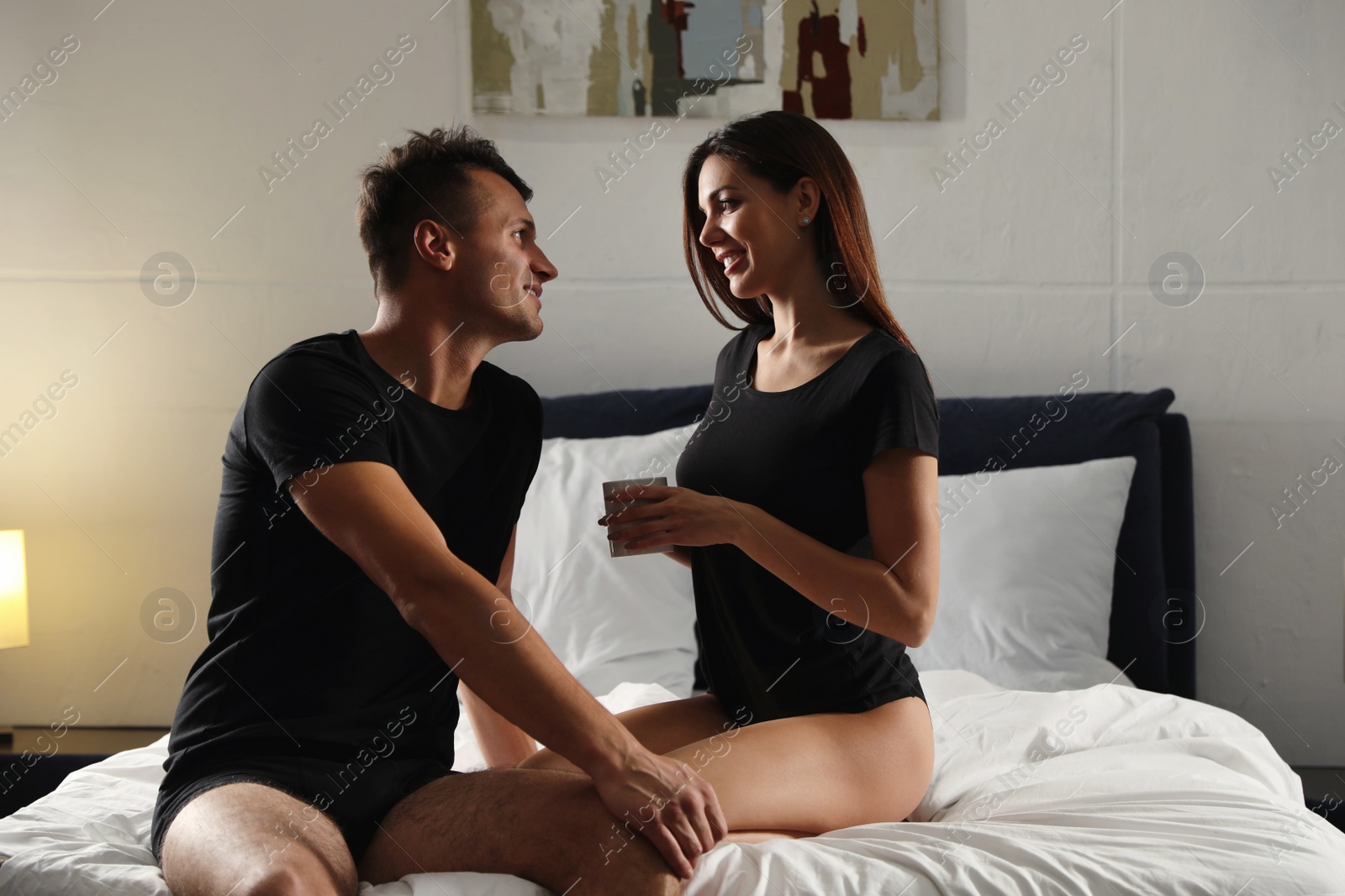 Photo of Happy couple wearing underwear in modern bedroom