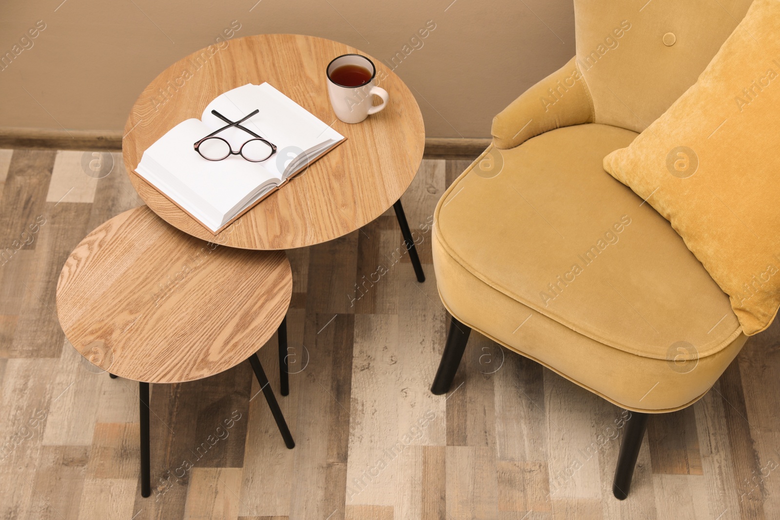 Photo of Wooden nesting tables near armchair in room. Interior design