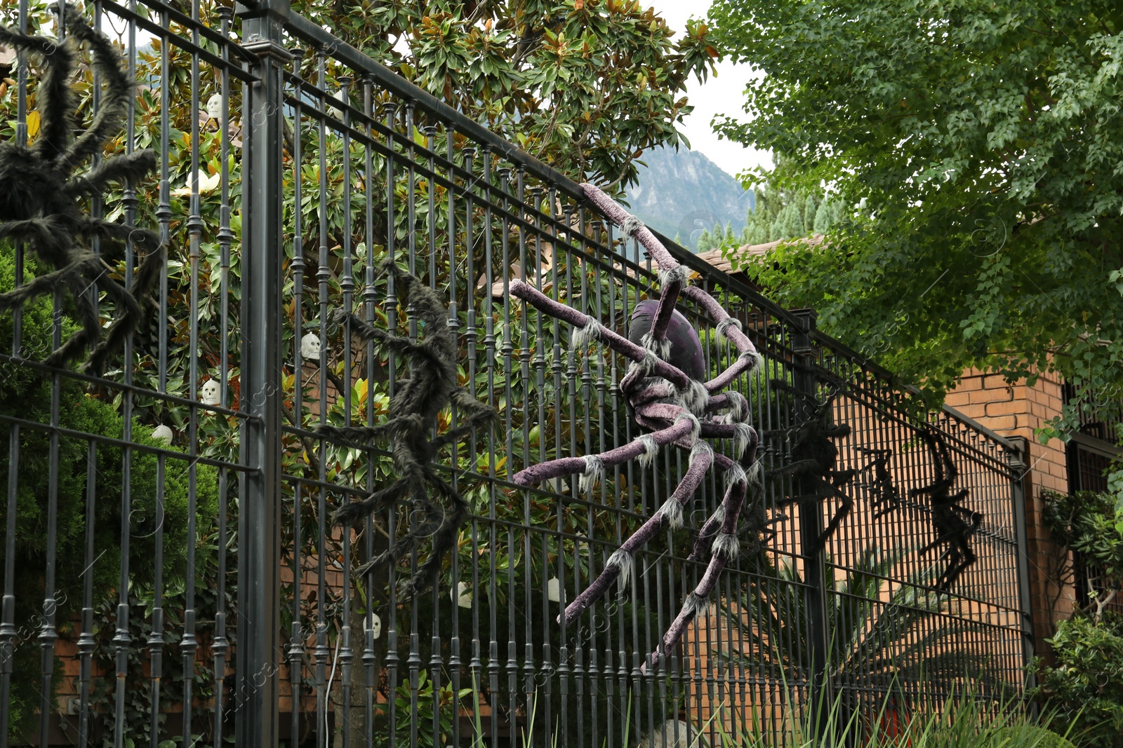 Photo of Big spider figures on black metal fence. Halloween decoration