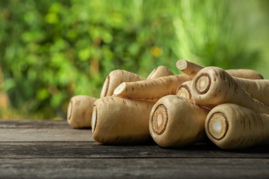 Photo of Delicious fresh ripe parsnips on wooden table outdoors