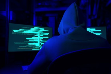 Photo of Hacker working with computers in dark room, back view. Cyber attack