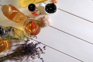 Photo of Different cooking oils and ingredients on white wooden table, above view. Space for text