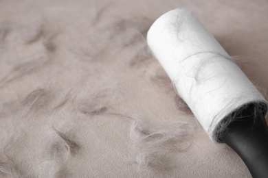 Modern lint roller and cat hair on light fabric, closeup