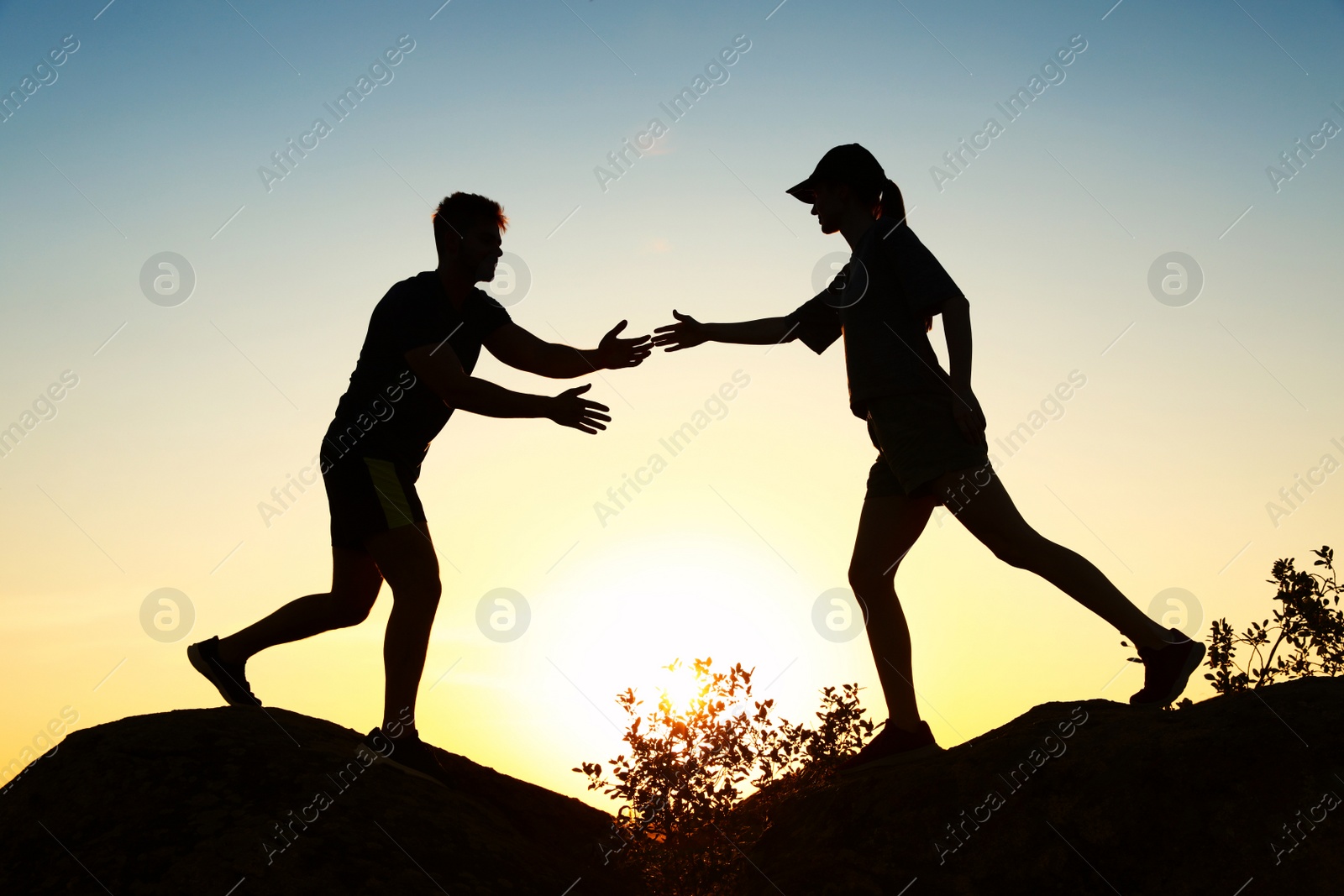 Photo of Hiker helping friend outdoors at sunset. Help and support concept