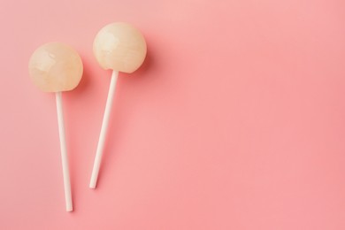 Photo of Tasty lollipops on pink background, flat lay. Space for text